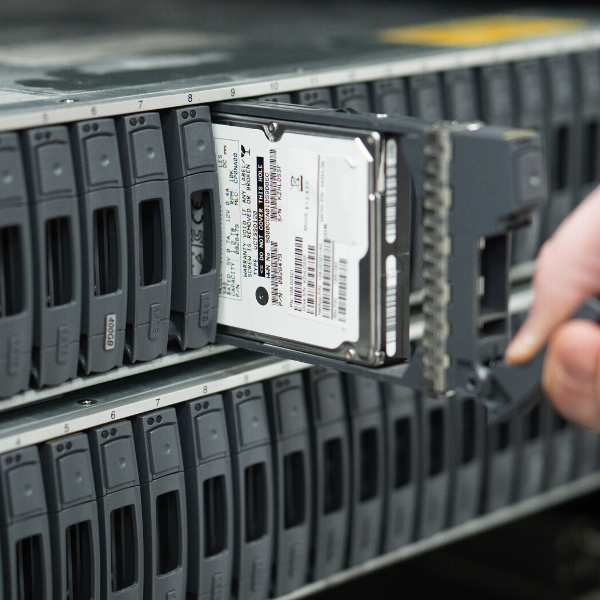 Person inserting a hard drive into a server rack in a data center