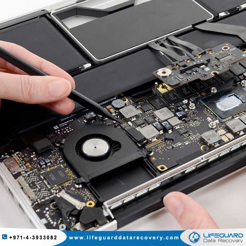 Close-up of a person repairing a laptop's internal components with a tool, Lifeguard Data Recovery logo and contact at the bottom